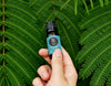 Hand holding essential oil in front of leaves