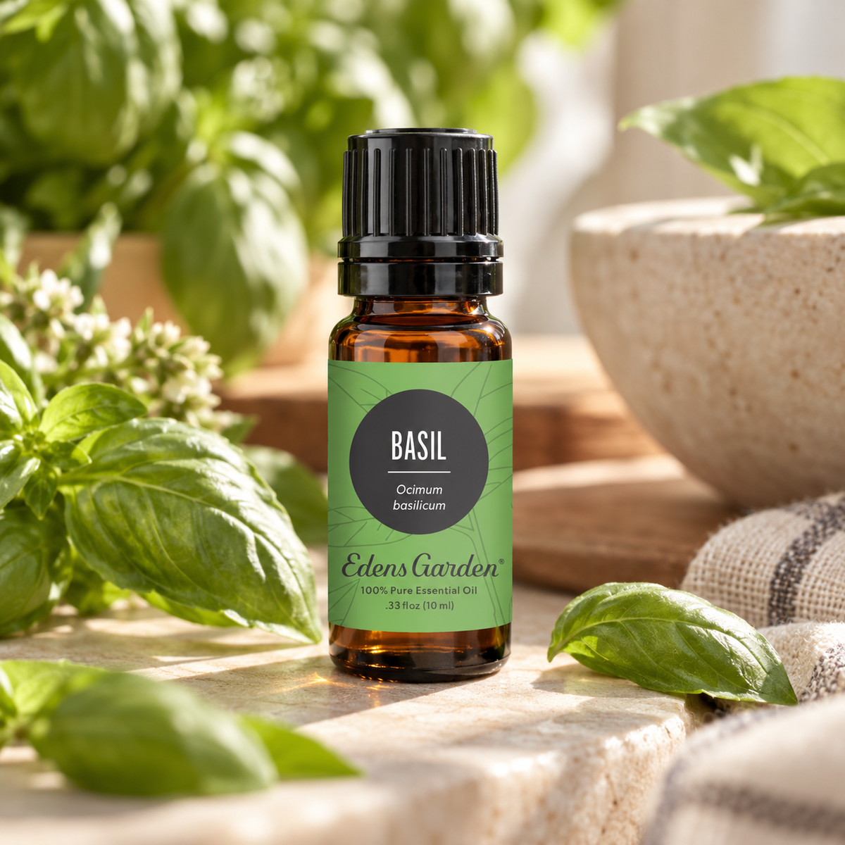 Edens Garden Basil Essential Oil 10 ml amber glass bottle surrounded by fresh basil leaves, delicate white flowers, and natural stone accents in a dreamy, sunlit garden setting.