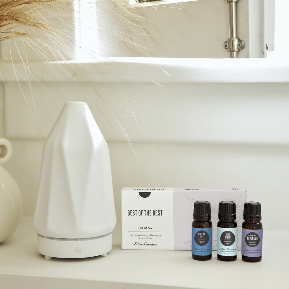 White diffuser and essential oil bottles on a shelf with a neutral background
