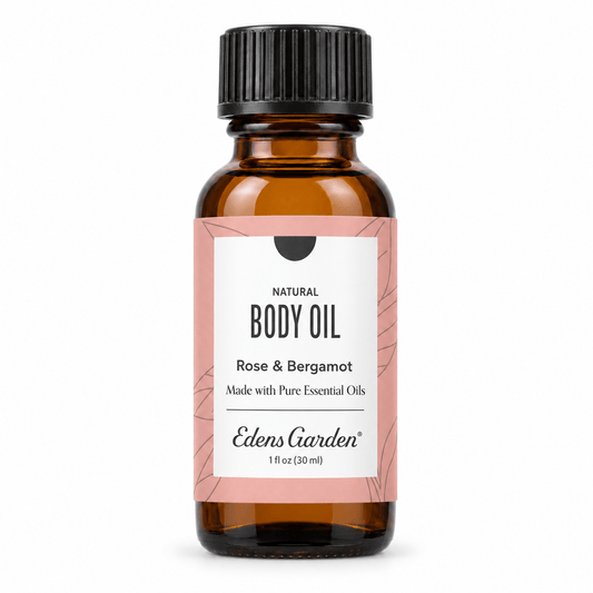 A 1 fl oz amber glass bottle of Edens Garden Natural Body Oil with Rose and Bergamot, featuring a white and pink label and a black ribbed cap, on a white background.