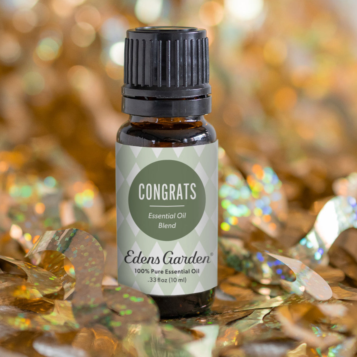 Edens Garden essential oil blend bottle on a reflective surface with a glittery background