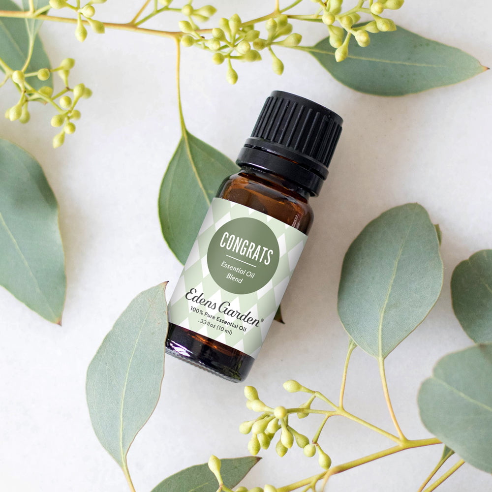 Eden's Garden essential oil blend bottle surrounded by green leaves on a light background