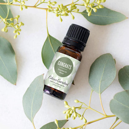 Eden's Garden essential oil blend bottle surrounded by green leaves on a light background