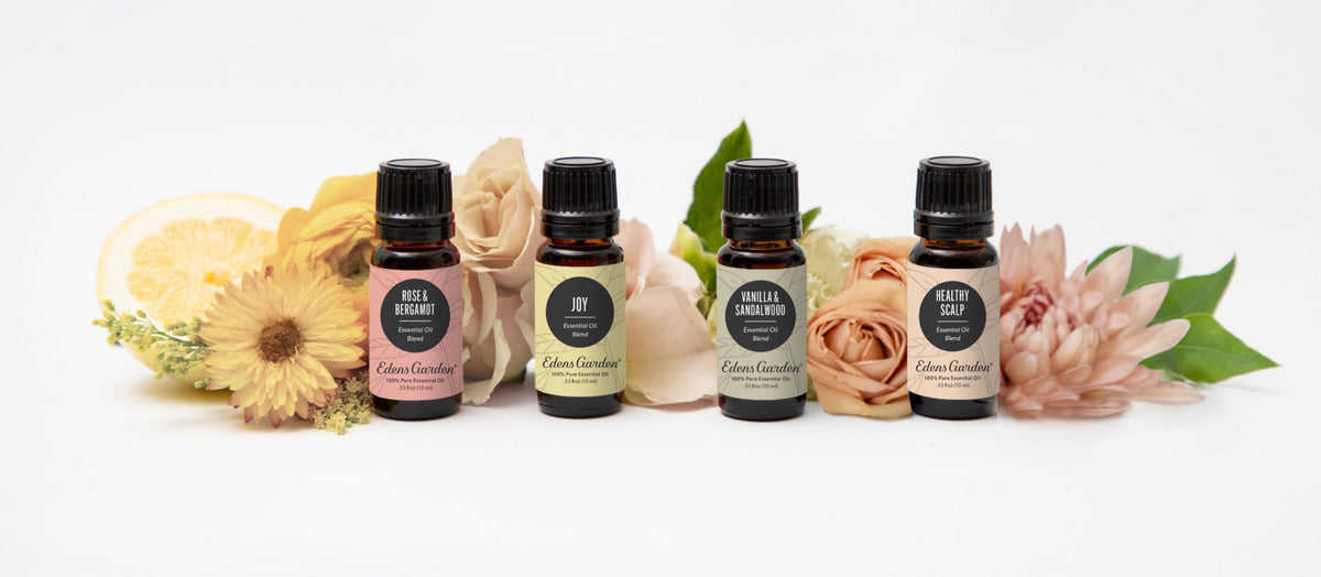 Four essential oil bottles with flowers in the background