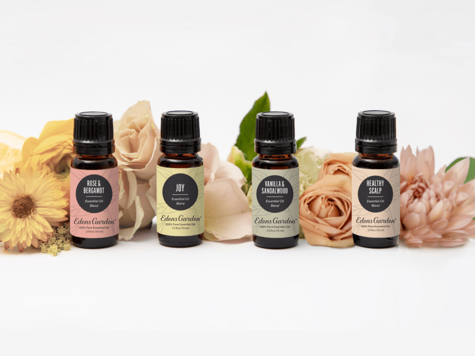 Four essential oil bottles with flowers in the background