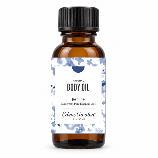 An amber glass bottle of Edens Garden Jasmine Natural Body Oil with a black ribbed cap and a white label decorated with blue watercolor flowers.