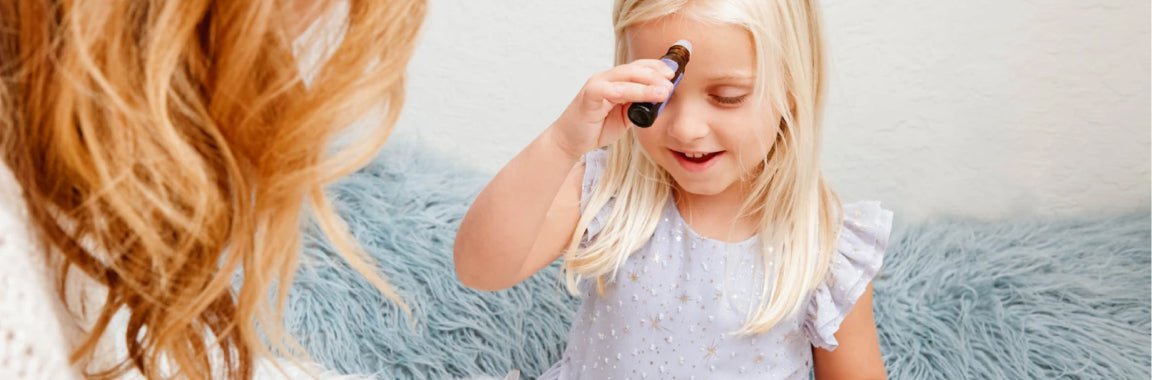 A little girl in a purple dress using an essential oil roll-on