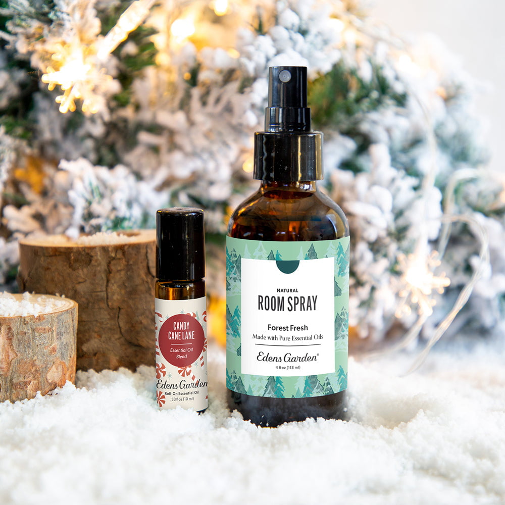 Two aromatherapy essential oil bottles with labels in front of a decorated Christmas tree.