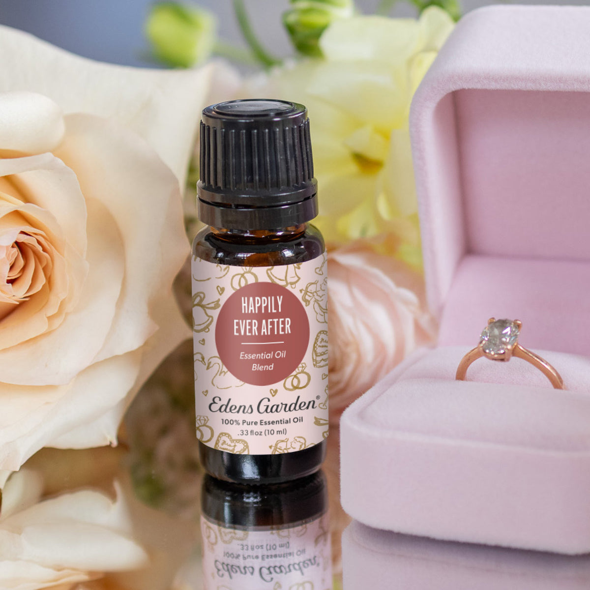Edens Garden Happily Ever After essential oil bottle with a ring in a pink box and flowers in the background