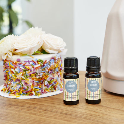 Two bottles of Edens Garden essential oils with a birthday cake in the background
