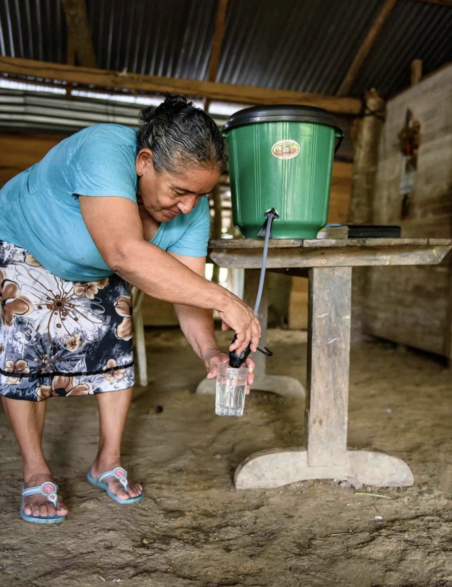 A promotional image of a woman pouring water for the One ATTA Time organization