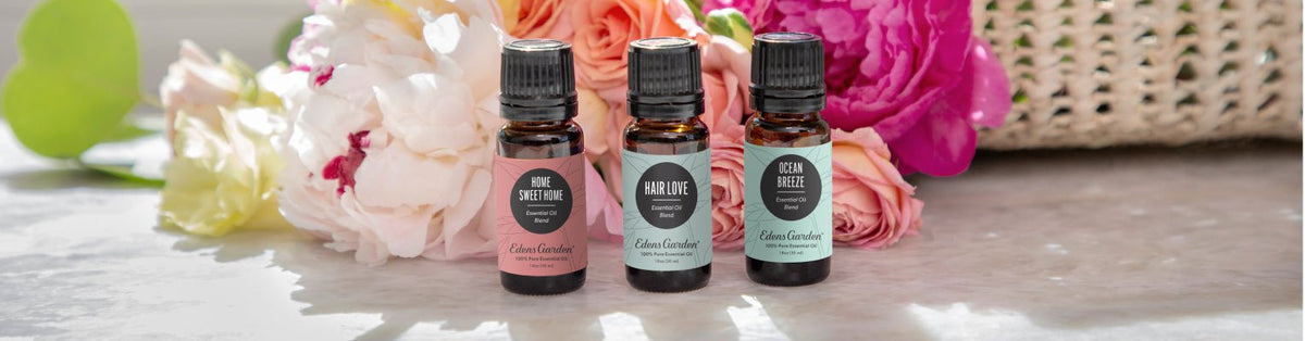 Three bottles of essential oil against a brightly lit background with flowers and a basket