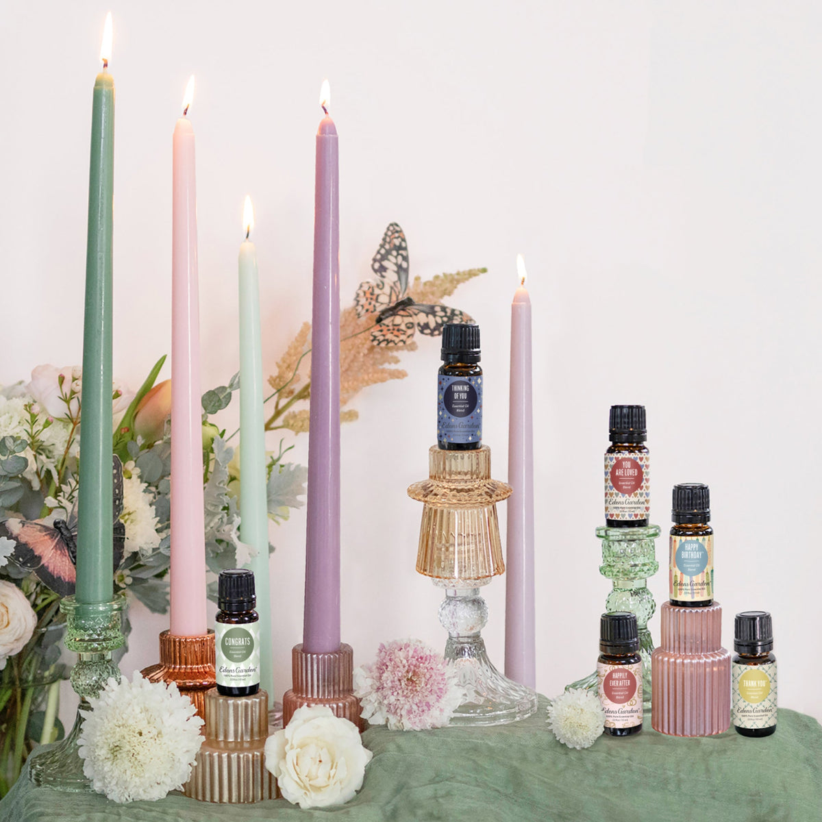 Candles and essential oil bottles on a table with flowers and decorative elements.
