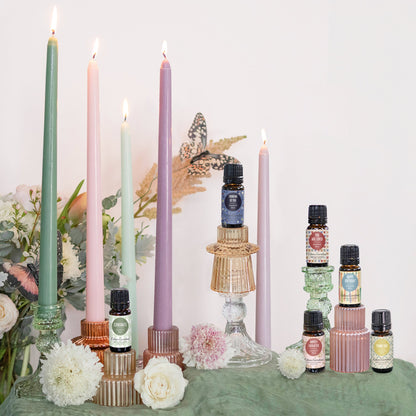 Candles and essential oil bottles on a table with flowers and decorative elements.