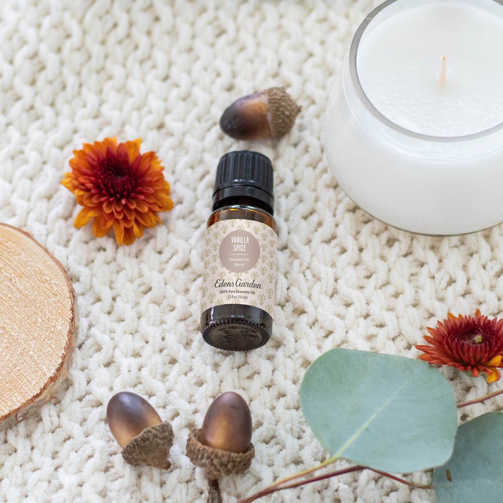 Bottle of Edema Garden oil with acorns, a flower, and a candle on a textured surface