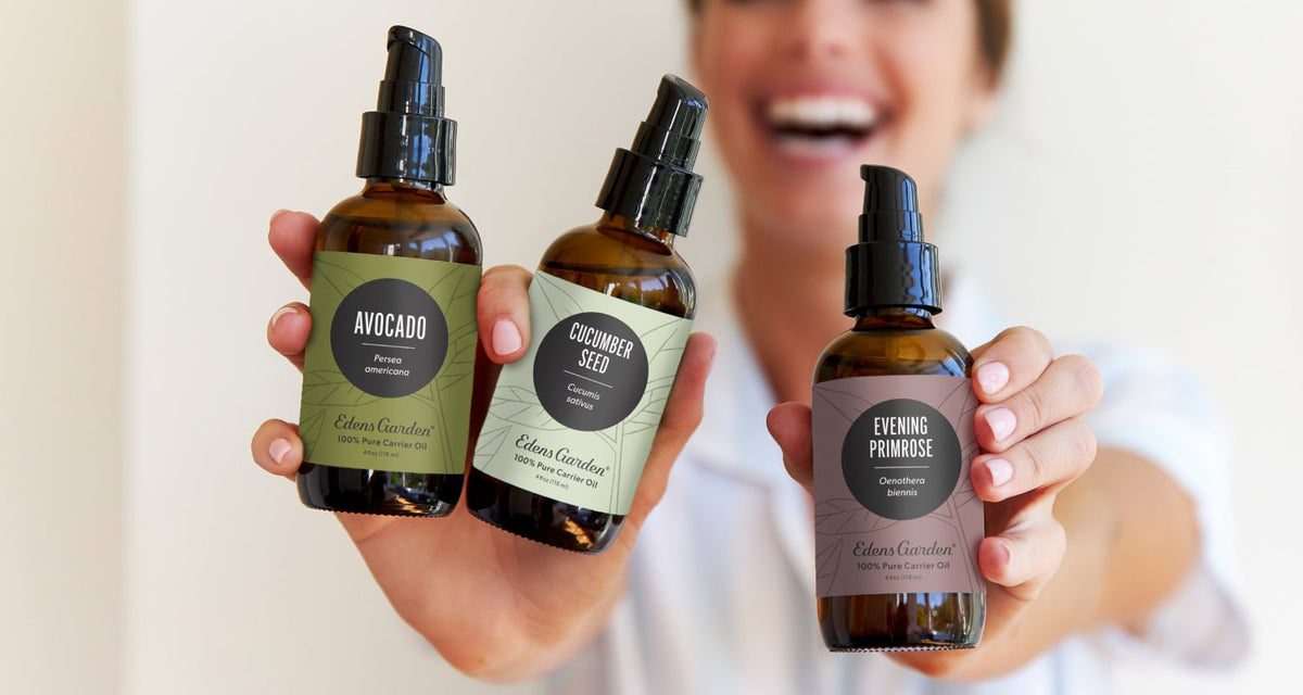 A woman smiling and holding up carrier oils