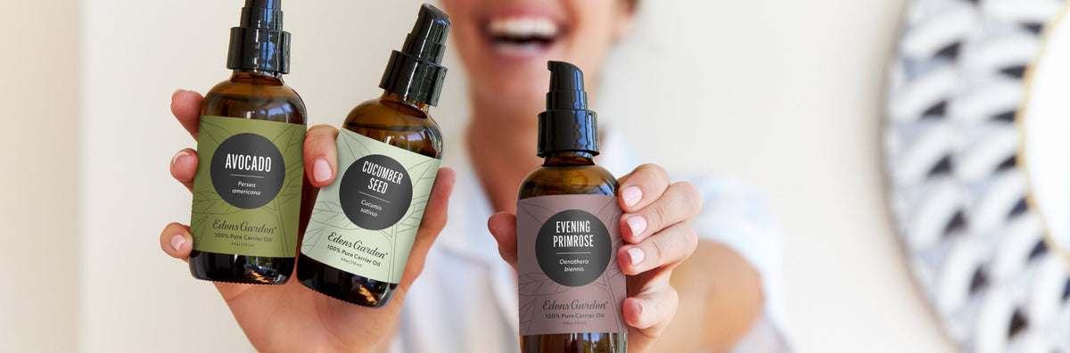 A woman smiling and holding up carrier oils